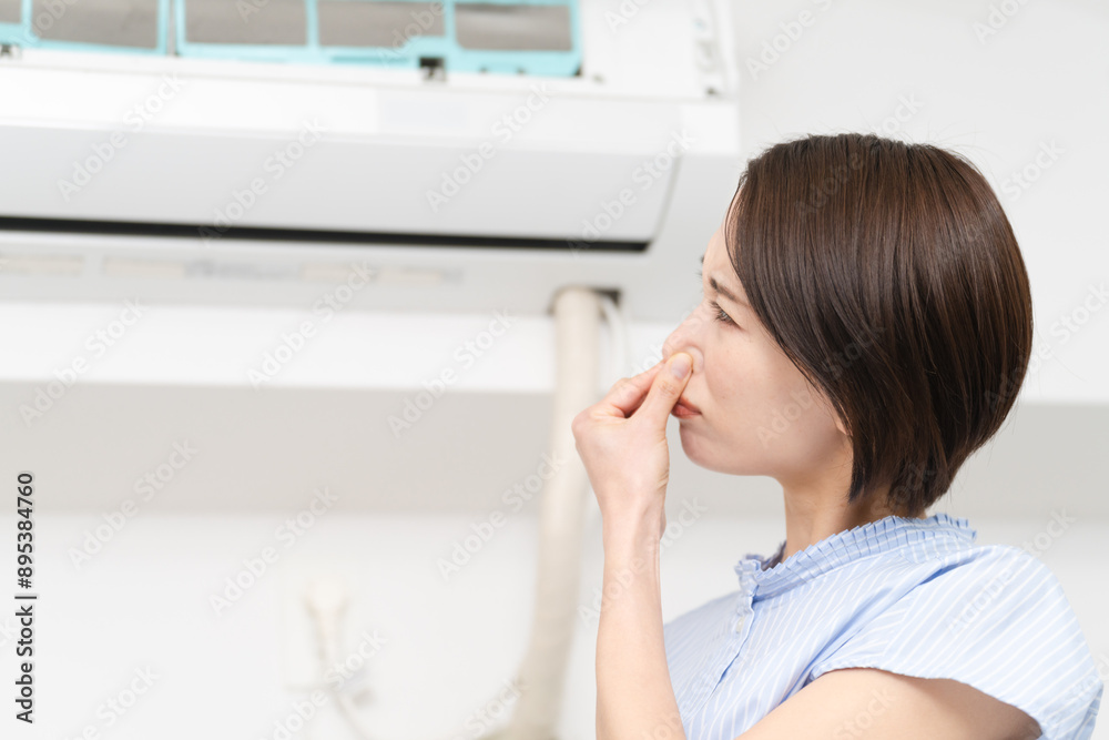 エアコンの匂いが気になる若い女性 ライフスタイルイメージ エアコンの匂いが気になる若い女性 ライフスタイルイメージ