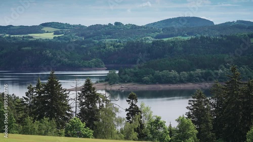 Wallpaper Mural A scenic view of a tranquil Vltava River surrounded by lush green hills and dense forests, offering a serene natural setting in a parallax video. Torontodigital.ca