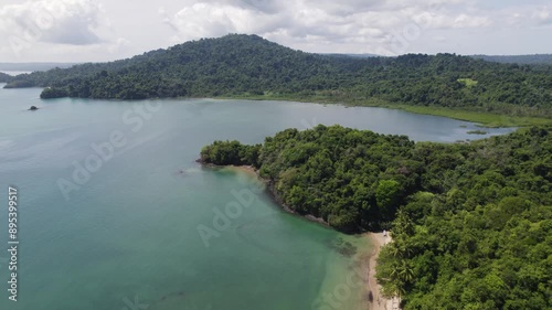 Aerial view of the serene Coiba Island beach in Panama, showcasing lush greenery, clear waters, and anchored boats. pull back shot photo