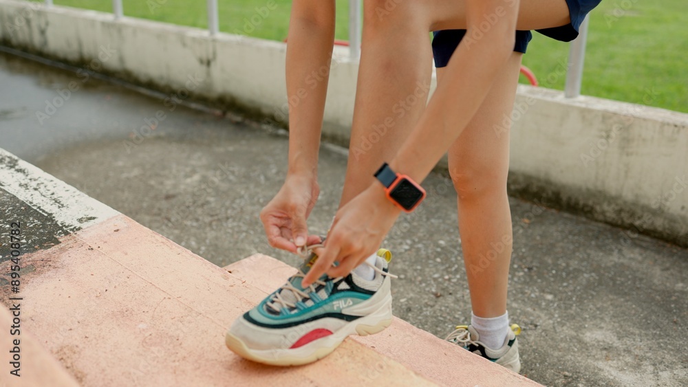 A woman is putting on her shoes on a concrete step