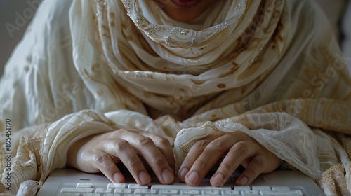 Mid-aged hijab girla??s hands, tidy white workspace, typing data into a laptop, close-up perspective, still life photo. photo