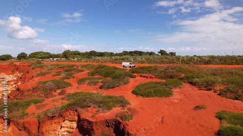 4K drone video flying out to reveal a couple standing on a cliff edge looking at the beautiful ocean views at Gantheaume Point in Broome, Western Australia. There campervan is in the background. photo