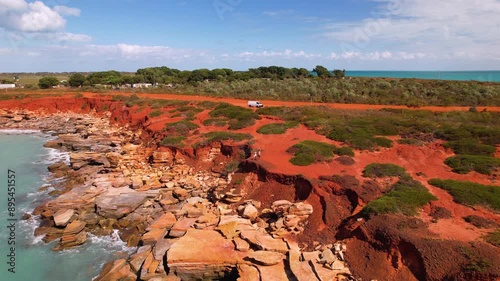 4K drone video of Gantheaume Point in Broome, Western Australia. The drone flies in to reveal a couple standing on the cliff edge with their campervan behind them admiring the unique landscape. photo