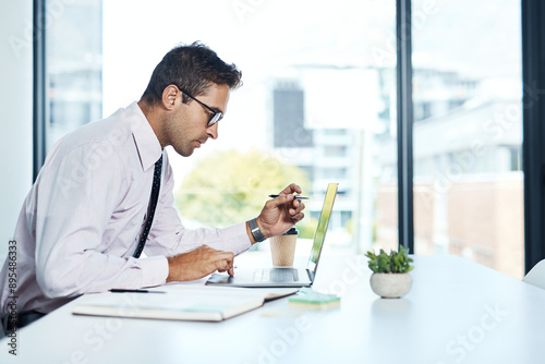 Accounting, laptop and reading with financial advisor man at desk in office for decision or planning. Computer, review and thinking with accountant or bookkeeper in workplace for portfolio management