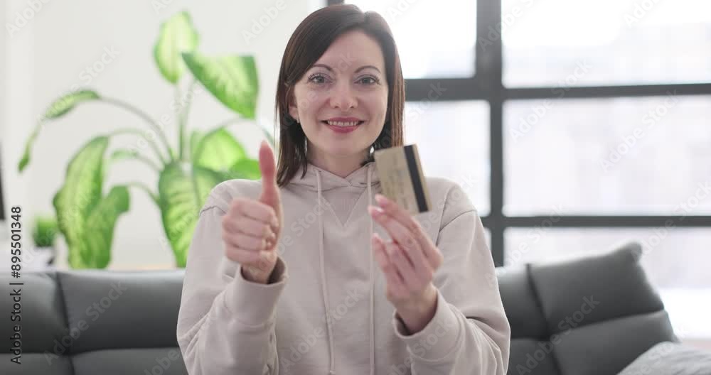 Young woman holds debit card and gives thumbs-up gesture Young woman holds debit card and gives thumbs-up gesture