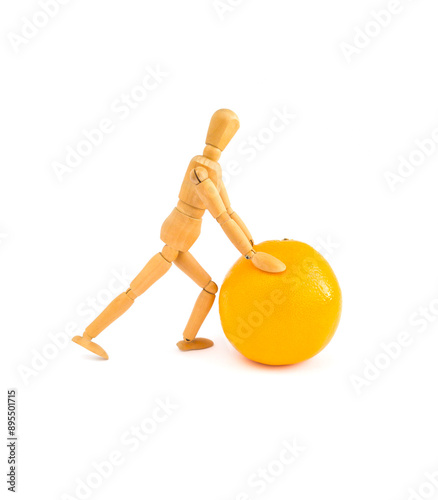 A wooden mannequin pushes an orange, Harvest concept, Isolated, White background