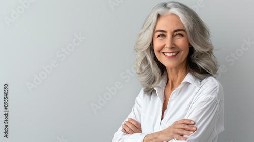 Handsome woman 50s mid age beautiful physically fit well groomed senior model grey hair stylish smiling Healthy face skin care skincare hair care fitness dental off center copy space gray background