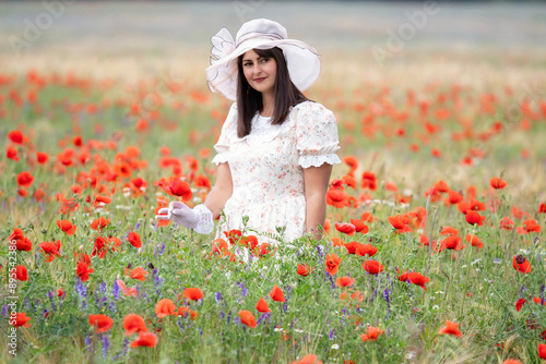 Lady in retro look stands in poppy field photo