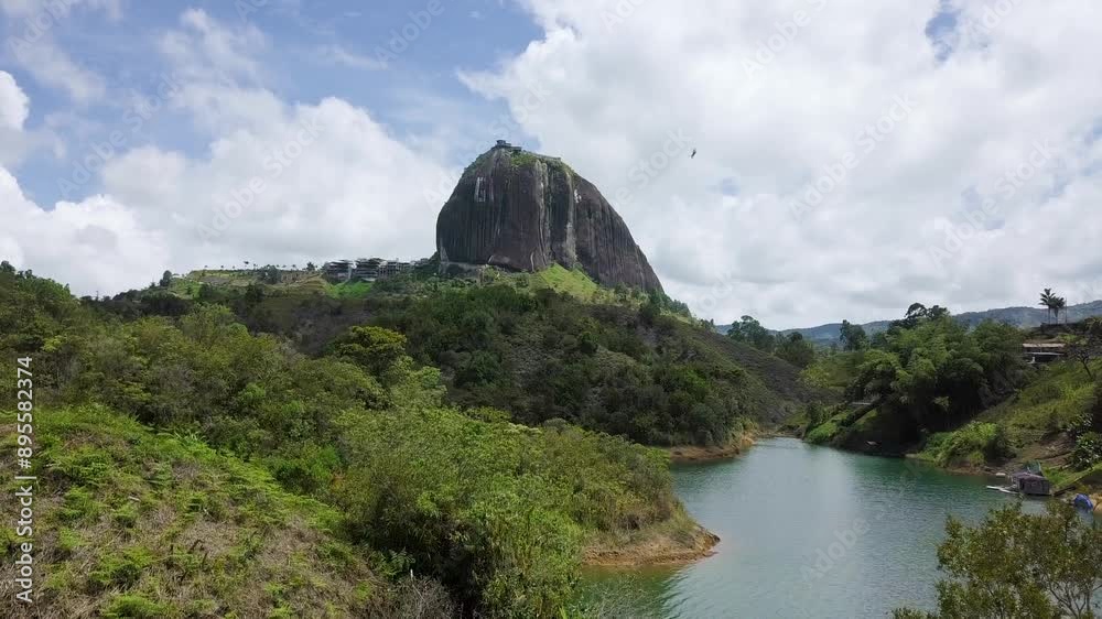 Stunning aerial view of The Rock of Penol in Guatape, Colombia, surrounded by lush greenery and serene water bodies. push forward shot
