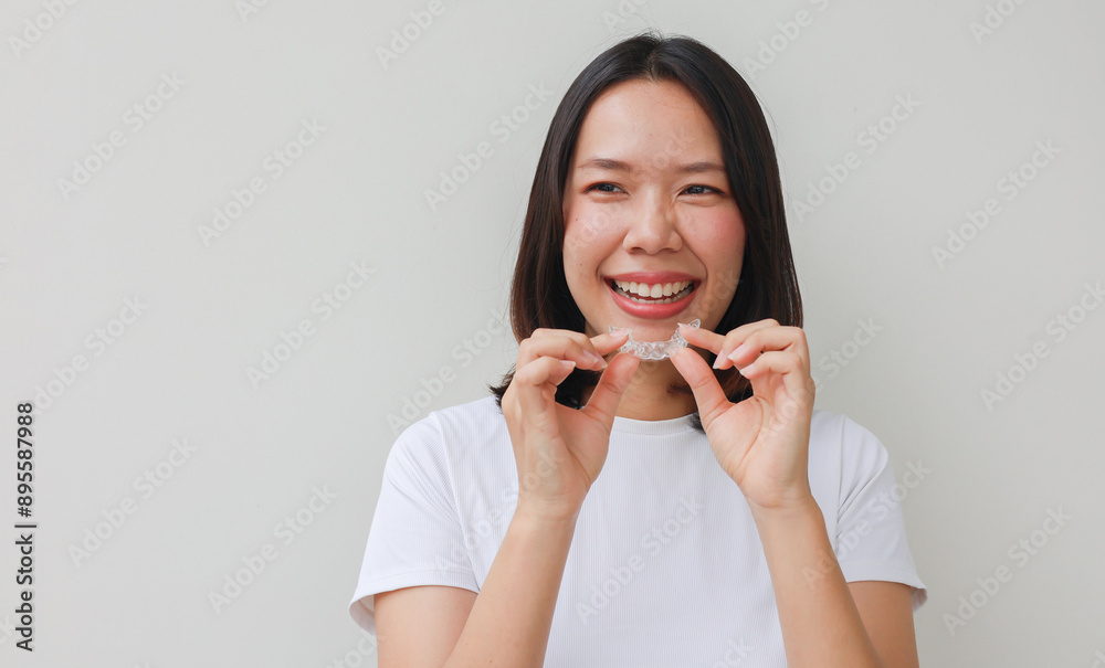close up young asian woman smiling with hand holding dental aligner retainer (invisible) at dental clinic for beautiful teeth treatment course concept close up young asian woman smiling with hand holding dental aligner retainer (invisible) at dental clinic for beautiful teeth treatment course concept