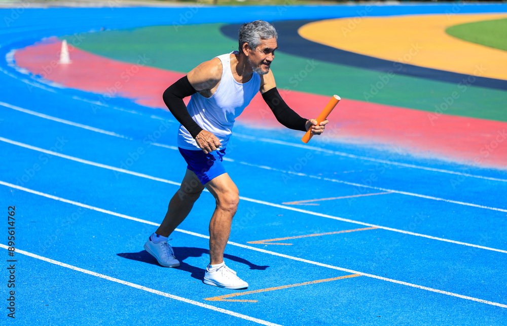 Fototapeta premium Senior Asian athlete is practicing running in the professional blue track for professional exercise, sport training workout and healthy for longevity concept