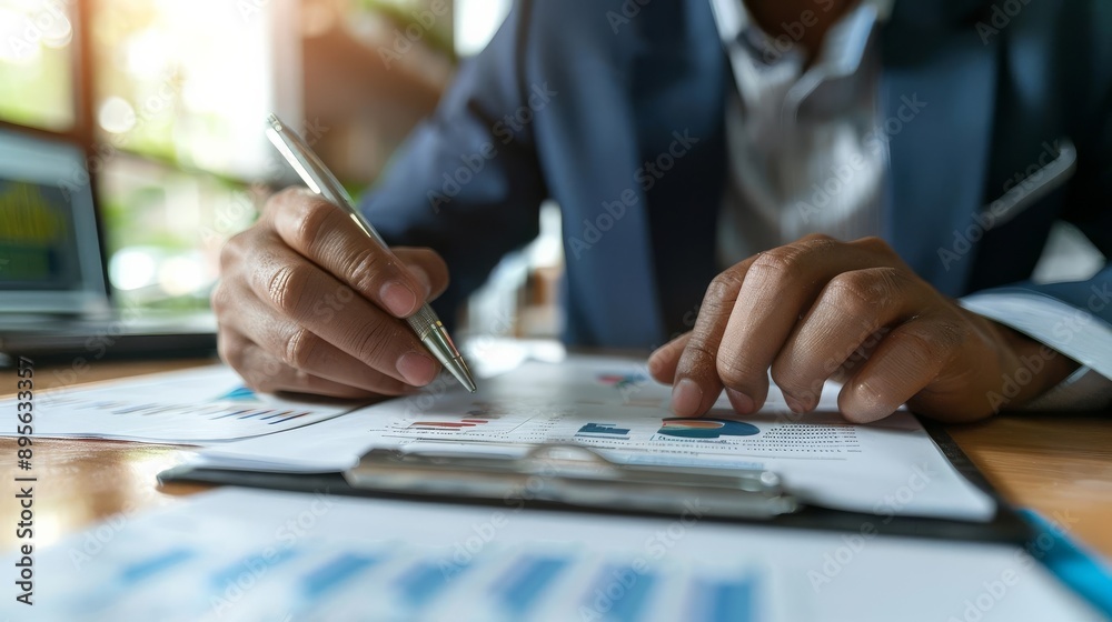 Businessman working on financial document at desk, analyzing charts and data in an office setting, focusing on financial growth. Businessman working on financial document at desk, analyzing charts and data in an office setting, focusing on financial growth.