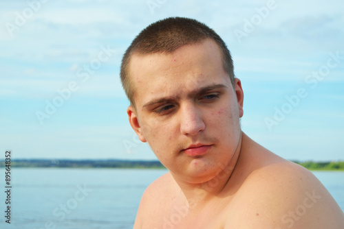 A fashionable autistic guy of 19 years old on a summer walk on the beach