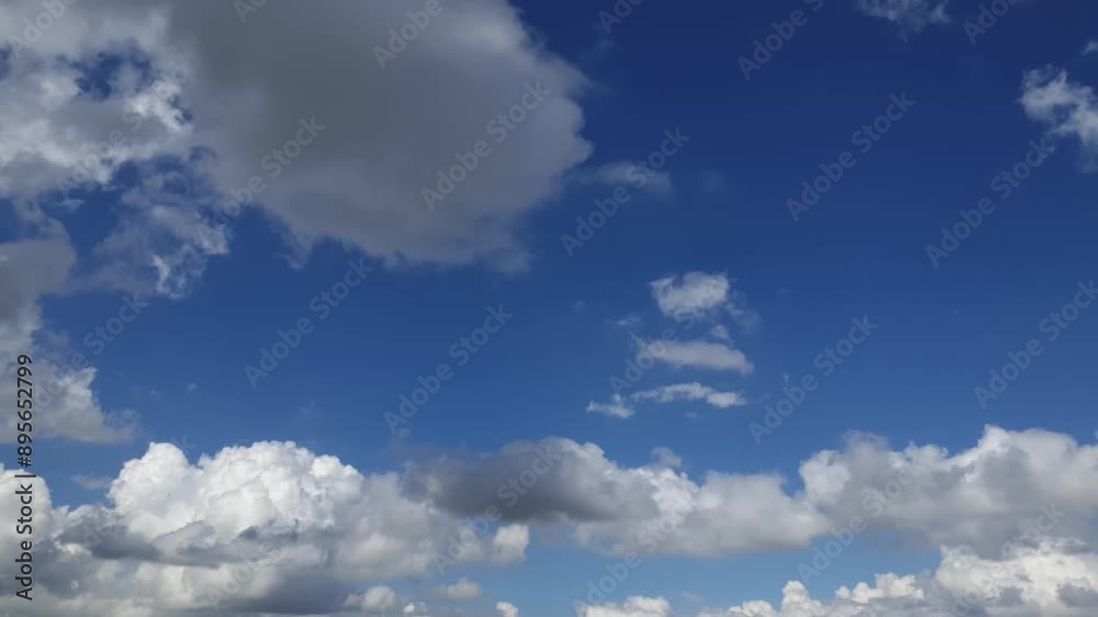 Blue sky in summer with cumulus clouds moving past high above the horizon in a beautiful motion time lapse Blue sky in summer with cumulus clouds moving past high above the horizon in a beautiful motion time lapse