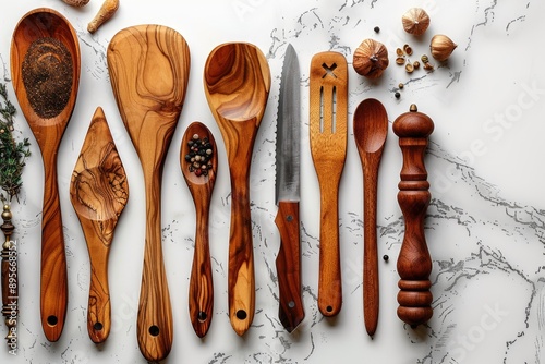 A collection of wooden kitchen utensils arranged on a white marble surface with spices and garlic photo