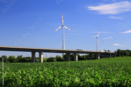 Obraz na płótnie Wind turbines beside German Autobahn bridge over green field under clear blue sky w salonie
