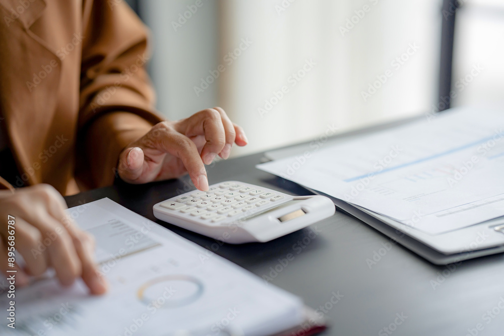 Businesswoman reading business information and working about calculating tax Businesswoman reading business information and working about calculating tax