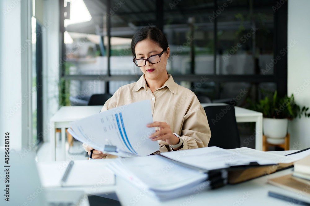 Middle age asian woman working on documents data at contemporary office Middle age asian woman working on documents data at contemporary office