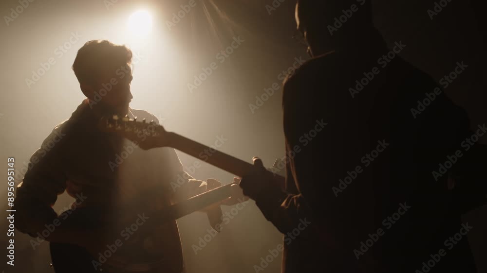 Rock music band playing electric guitars while performing on dimly lit foggy stage during concert