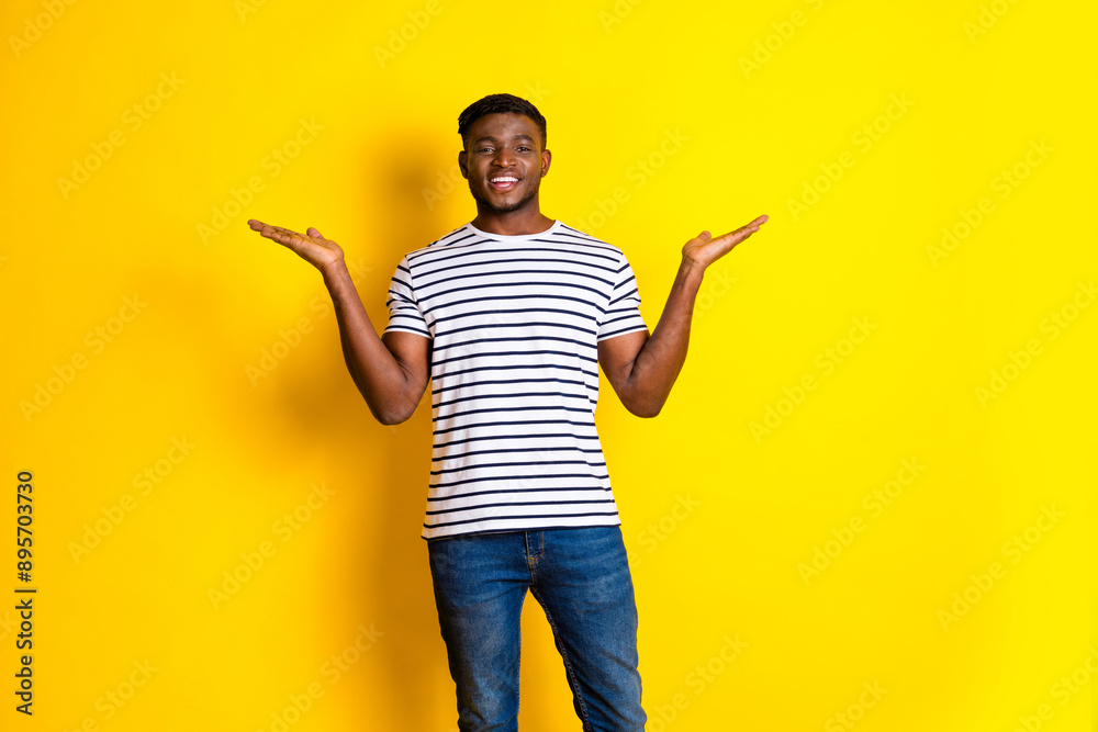 Portrait of nice young man hold empty space wear striped t-shirt isolated on vibrant yellow color background Portrait of nice young man hold empty space wear striped t-shirt isolated on vibrant yellow color background