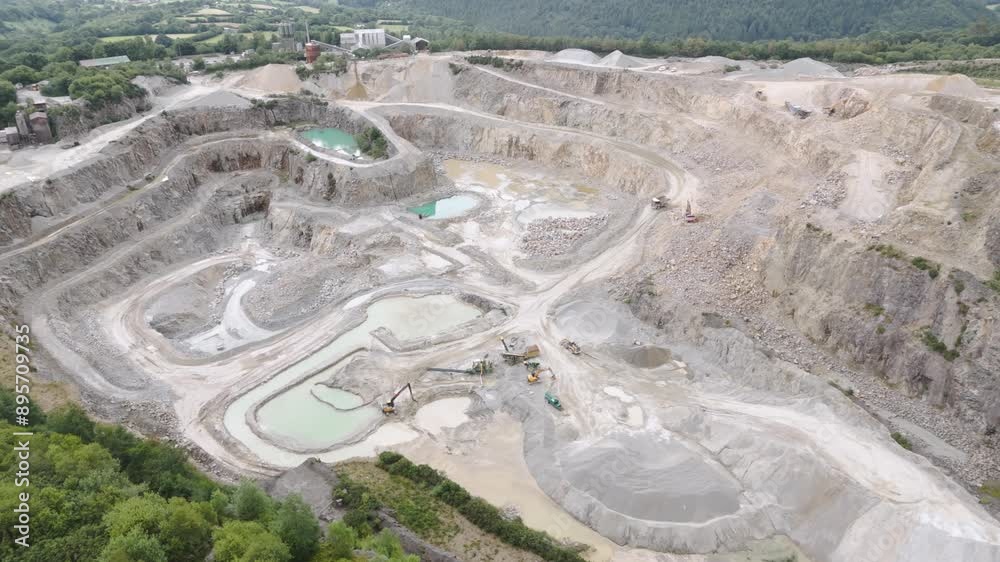 Aerial reveal of a large aggregate quarry mining operation, showcasing extensive excavation areas and machinery
