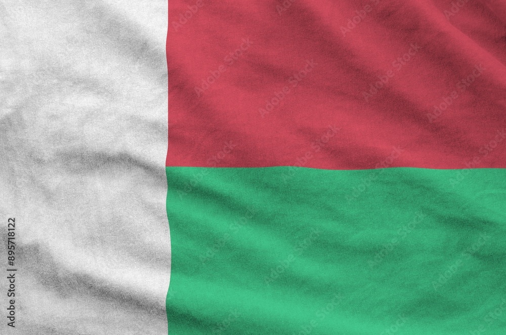 Madagascar flag depicted on folded wavy fabric of old cloth close up Madagascar flag depicted on folded wavy fabric of old cloth close up