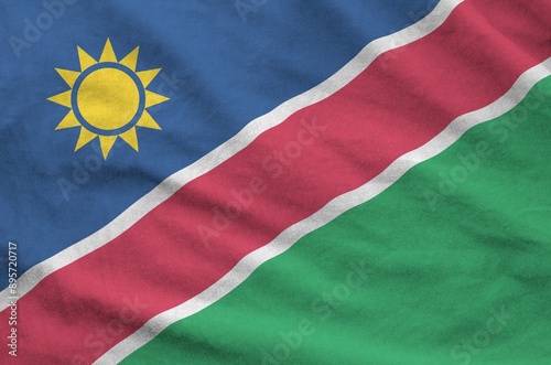 Namibia flag depicted on folded wavy fabric of old cloth close up photo