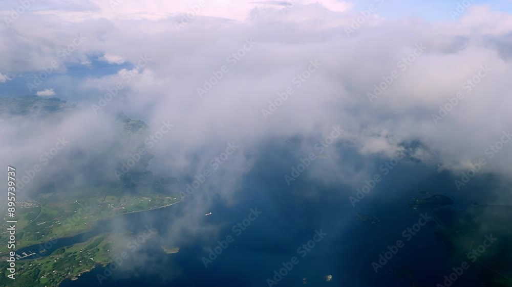Aerial view through the clouds to the Norwegian fjords, shadow of an airplane on a cloud. Top view from the clouds to the sea bay with coastal hills Aerial view through the clouds to the Norwegian fjords, shadow of an airplane on a cloud. Top view from the clouds to the sea bay with coastal hills