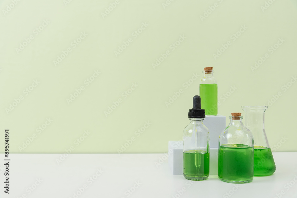 Assorted Laboratory Glassware with Green Liquid on White Surface Assorted Laboratory Glassware with Green Liquid on White Surface