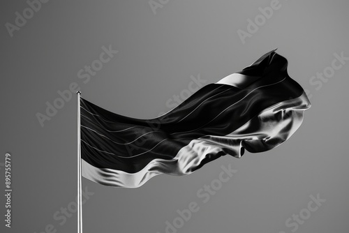 A waving black and white flag against a gray background, capturing the motion of wind through its fabric.