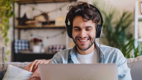 Happy man student wearing headphones study online using laptop on blurred home background