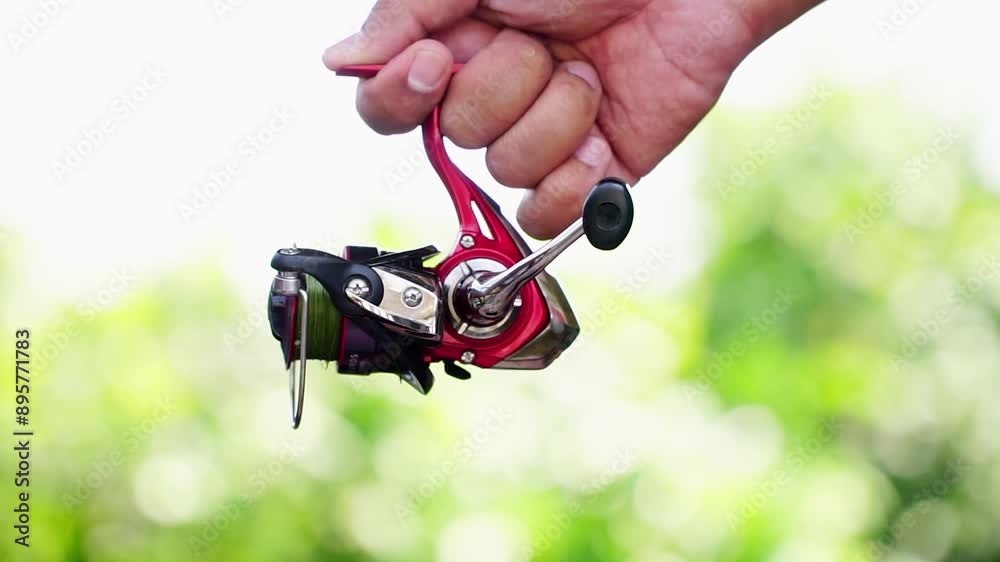 A fishing reel held in a mans hand. spinning rod. fishing as a hobby and outdoor sport. A fishing reel held in a mans hand. spinning rod. fishing as a hobby and outdoor sport.