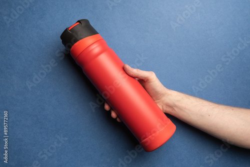 red thermos in the hands of man
