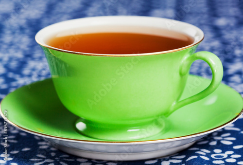 Close up of tea in a green porcelain teacup with matching saucer. photo