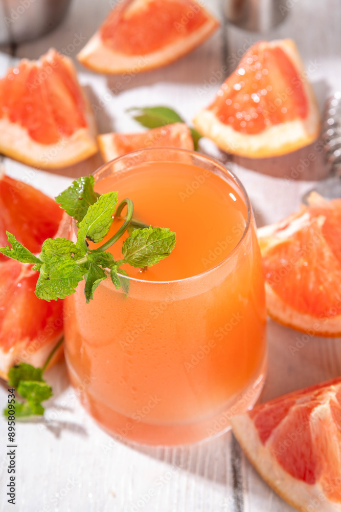 Cold grapefruit mojito drink, tequila Pink Paloma, refreshment citrus lemonade with pink grapefruit juice and mint, on white wooden table, copy space Cold grapefruit mojito drink, tequila Pink Paloma, refreshment citrus lemonade with pink grapefruit juice and mint, on white wooden table, copy space