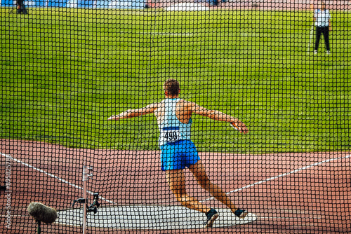 discus throw, male athlete makes an attempt, view through grid photo