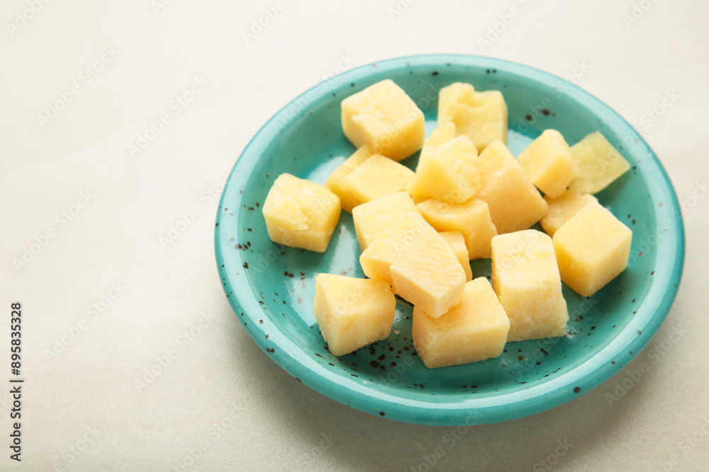 Cheese cubes on blue plate on light background. Parmesan Cheese cubes on blue plate on light background. Parmesan