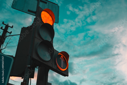 Car traffic light, with a red burning arrow, against the background of the sunset sky