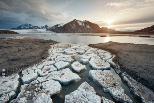 Beautiful landscape showcasing cracked ice pieces on a water body with majestic mountains and a serene sunset in the background, highlighting nature's pristine beauty.