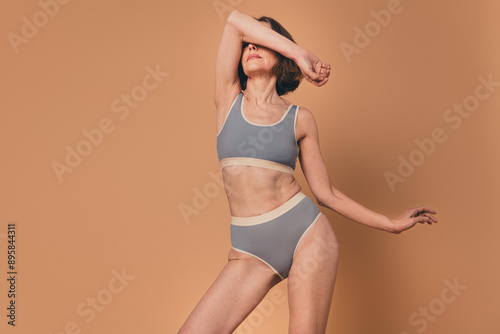 No filter photo of charming gorgeous woman posing athletic sporty shape isolated on beige color background © deagreez