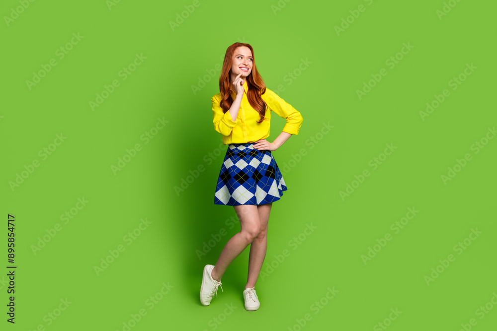 Full length photo of lovely young lady look empty space minded dressed stylish yellow garment isolated on green color background Full length photo of lovely young lady look empty space minded dressed stylish yellow garment isolated on green color background