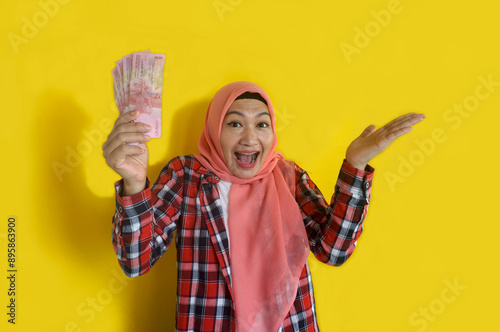 Young Asian Muslim Woman Showing Happy Surprise Face Expression While Holding Paper Money photo