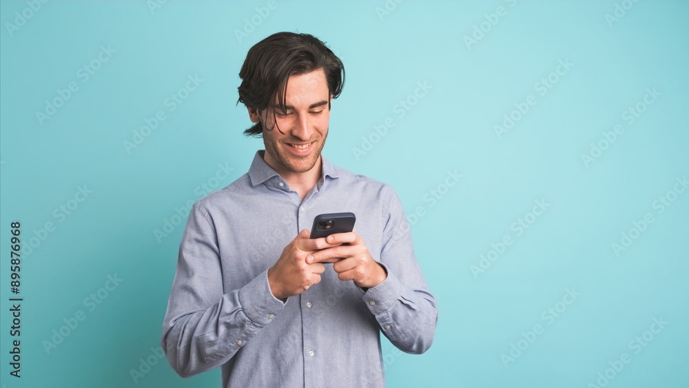 Happy adult man using smartphone in blue studio Happy adult man using smartphone in blue studio