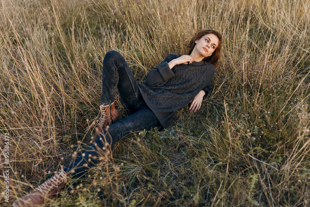 Confident woman posing in tall grass with hands on hips and looking directly at camera Confident woman posing in tall grass with hands on hips and looking directly at camera