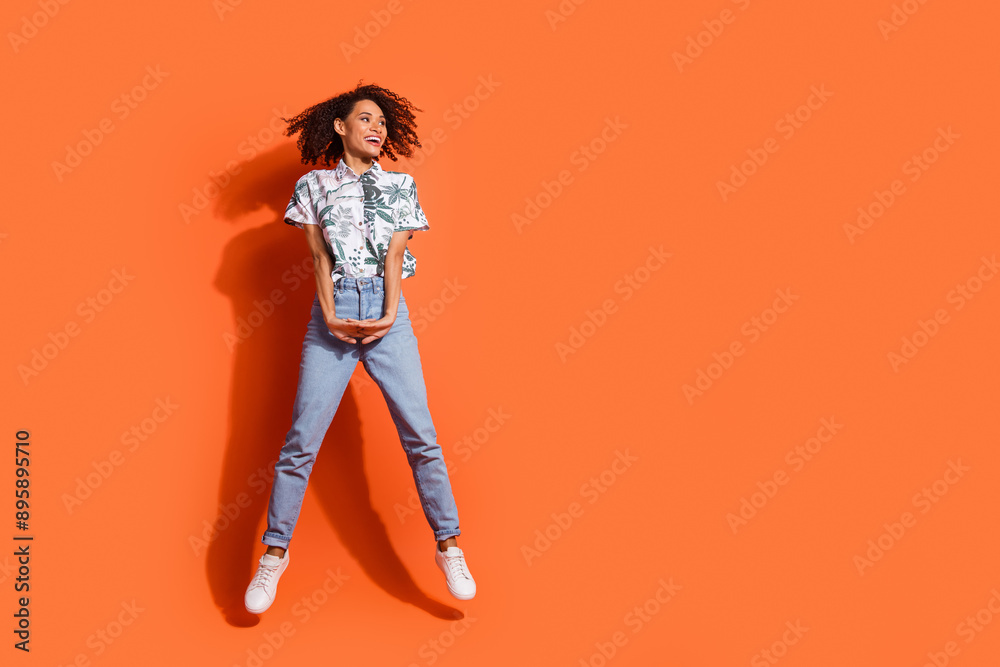 Full body length photo of american cute woman in jeans and hawaiian shirt jumping look novelty isolated on orange color background Full body length photo of american cute woman in jeans and hawaiian shirt jumping look novelty isolated on orange color background