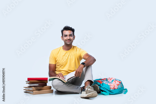 Foto Asian Indian young college or university student studying while sitting on floor