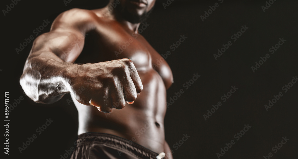 Male power. Confident muscular black guy showing strong fist to camera, panorama