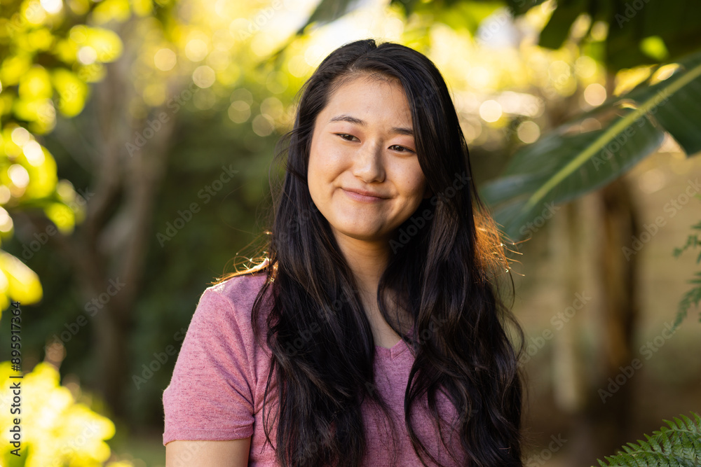 Smiling asian woman in pink shirt enjoying nature, standing outdoors in sunlight Smiling asian woman in pink shirt enjoying nature, standing outdoors in sunlight