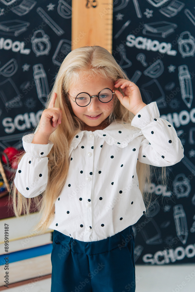 Fototapeta premium Emotional active excellent best schoolgirl in round glasses doing lessons in school, back to school, education. I do not want to study. 