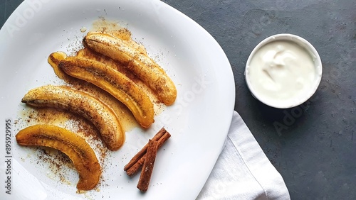 Caramelized bananas with cinnamon and yogurt on white plate.
